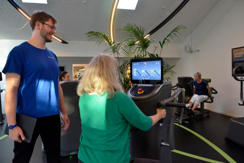 Trainer begleitet ein Mitglied am Trainingsgerät in einem bestehenden Kraftclub